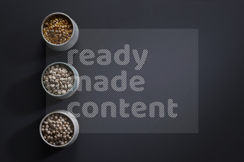 Legumes in pottery bowls on grey background
