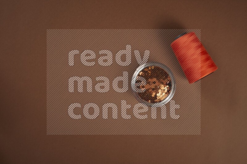 An orange collection of sewing and tailoring tools arranged on a brown background