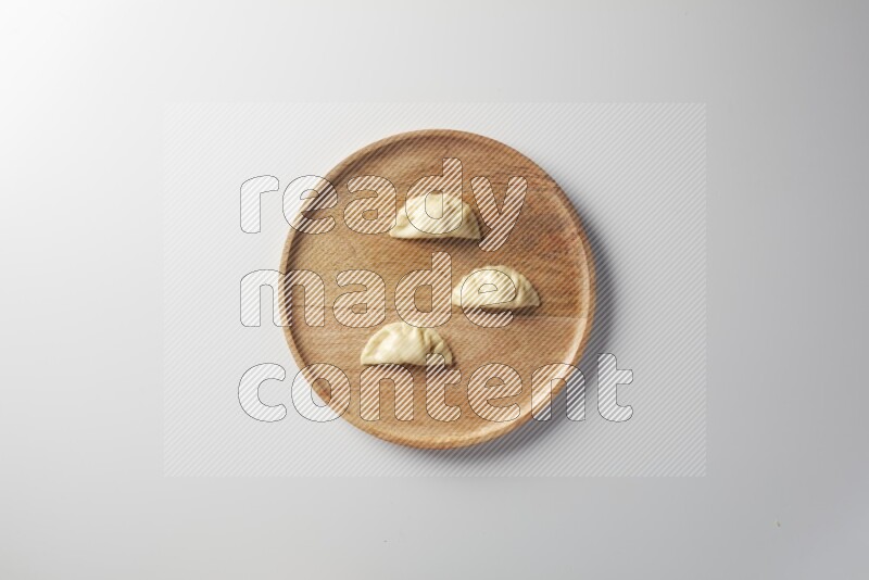 Three Sambosas on a wooden round plate on a white background