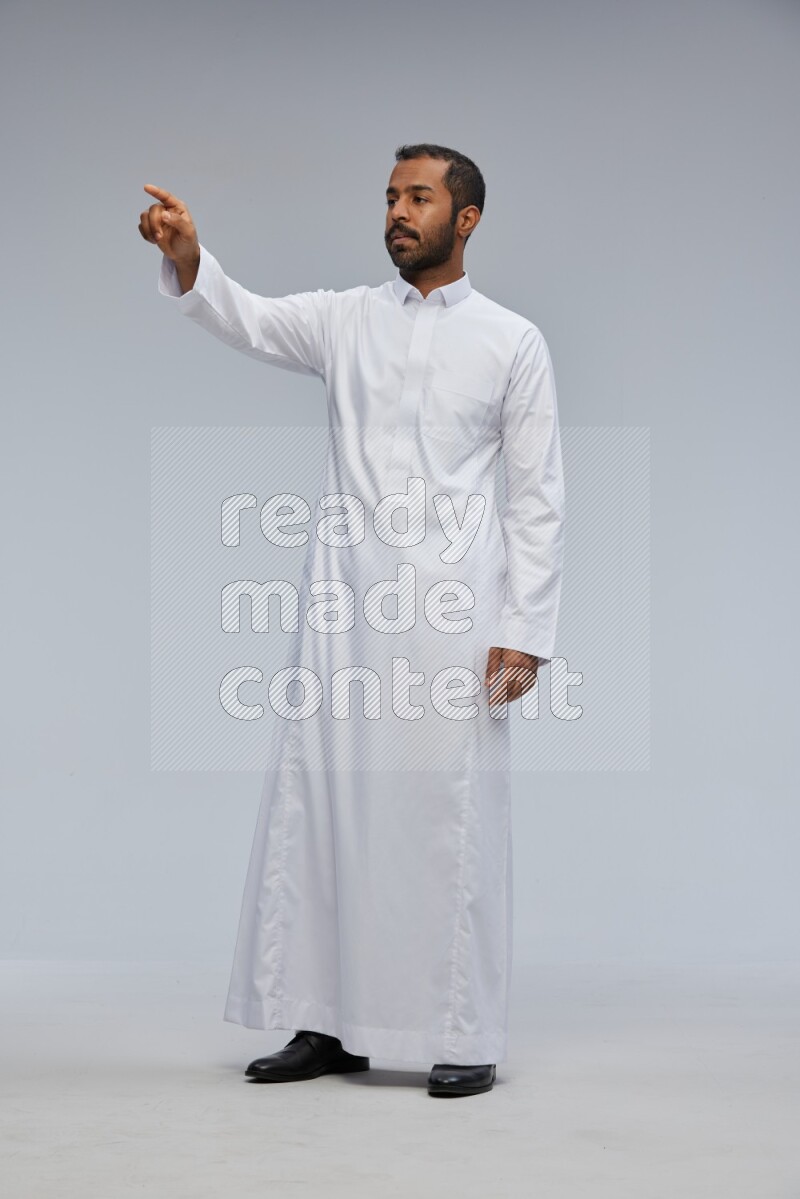 Saudi man Wearing Thob standing interacting with the camera on Gray background