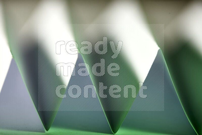 A close-up abstract image showing sharp geometric paper folds in white and green gradients