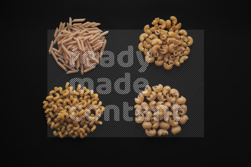 Different pasta types in bunches on black background