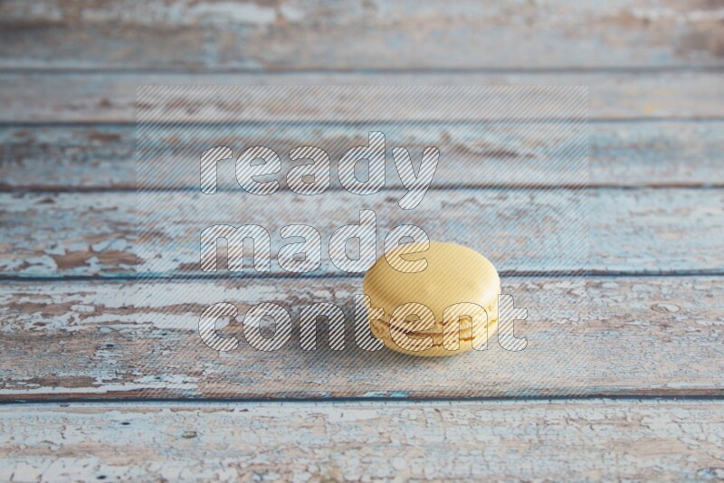 45º Shot of Yellow Vanilla macaron on light blue wooden background