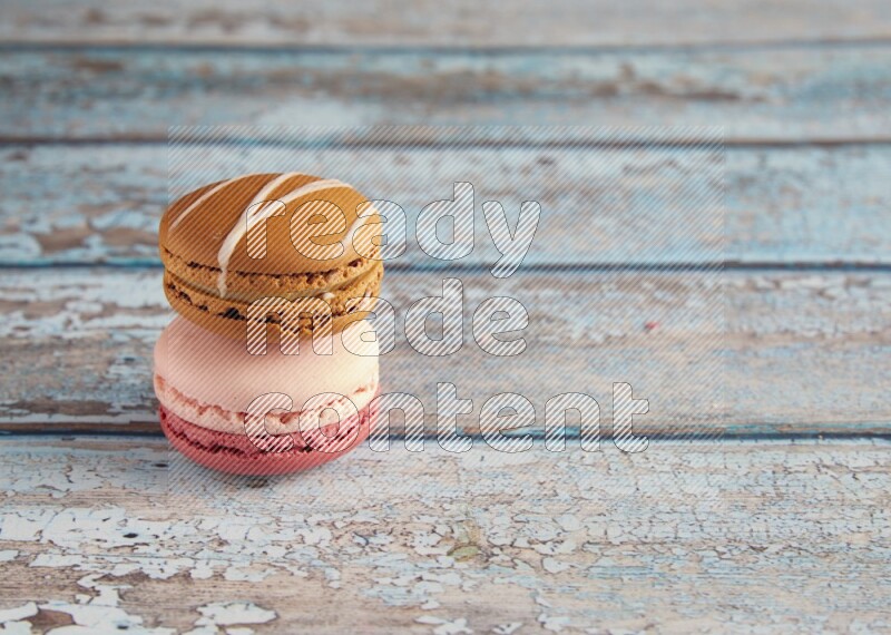 45º Shot of of two assorted Brown Irish Cream, and Pink Litchi Raspberry macarons on light blue background