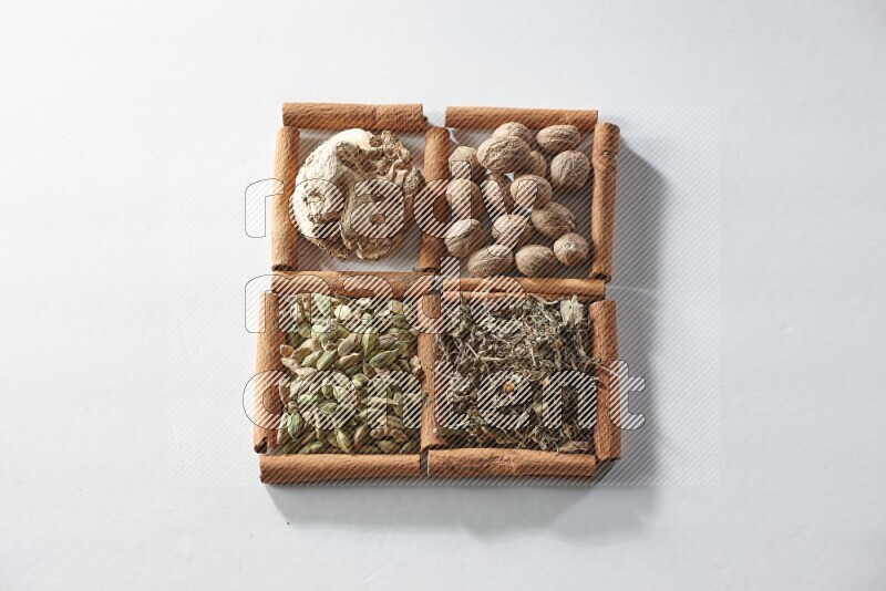 4 squares of cinnamon sticks full of nutmegs, dried ginger, cardamom and dried basil on white flooring