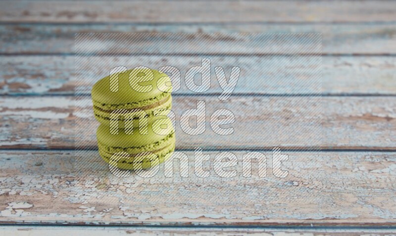 45º Shot of two Green Pistachio macarons on light blue wooden background
