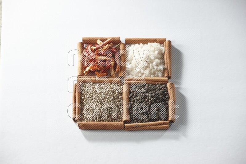 4 squares of cinnamon sticks full of red chilis, salt, white pepper, and black pepper on white flooring