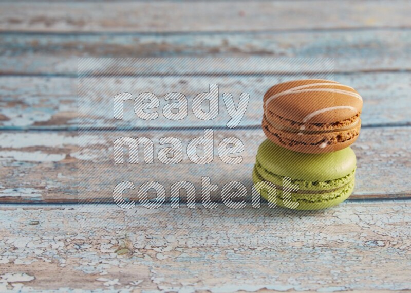 45º Shot of of two assorted Brown Irish Cream, and Green Pistachio macarons  on light blue background
