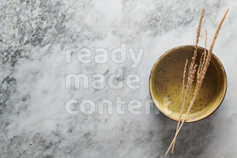 Wheat stalks on multicolored pottery oven plate on grey marble background