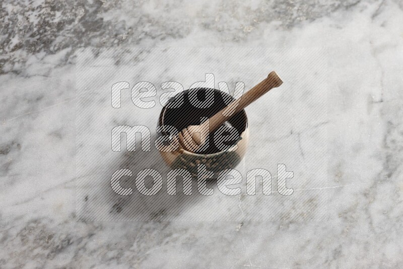 وعاء فخاري متعدد الألوان مع ملعقة عسل خشبية بداخله على خلفية من الرخام الرمادي