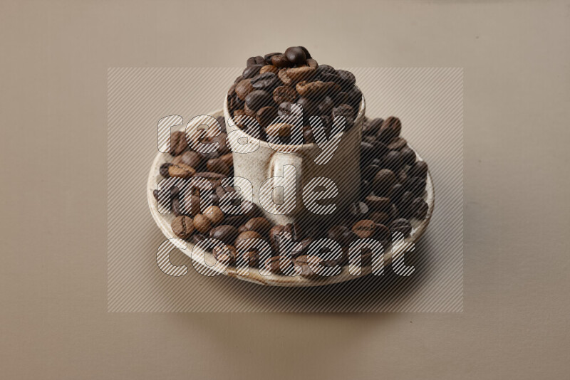 A beige pottery cup full of roasted coffee beans on beige background