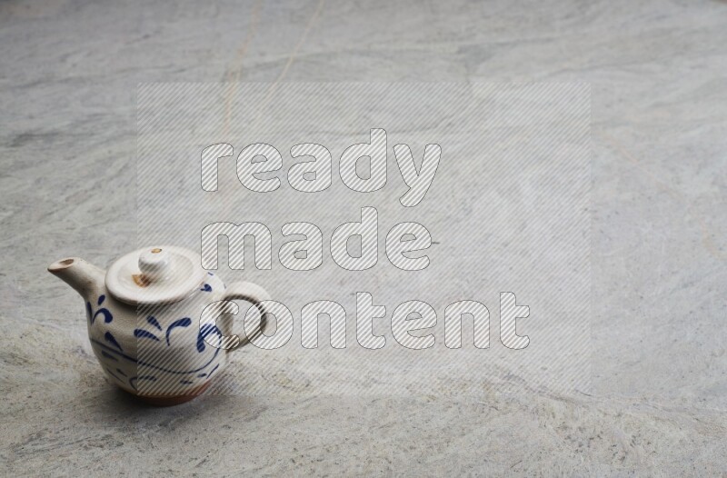 A pottery teapot on grey marble background
