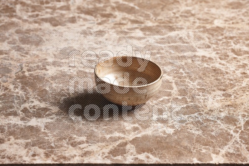 A beige pottery bowl on beige marble background