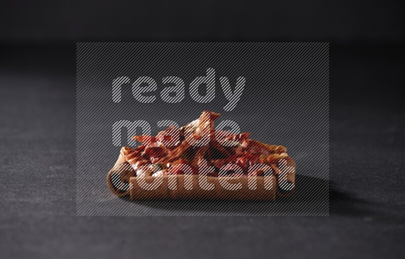 A single square of cinnamon sticks full of chilis on black flooring