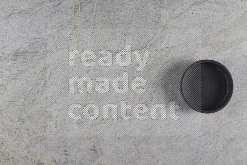 A black pottery bowl on grey marble background