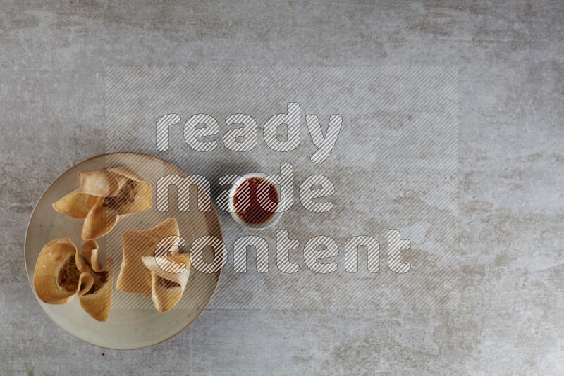 wonton cups with soy sauce ramkin on multi colored pottery on grey textured counter top
