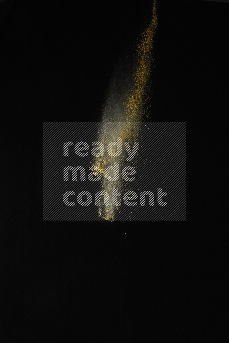 A side view of yellow powder explosion on black background