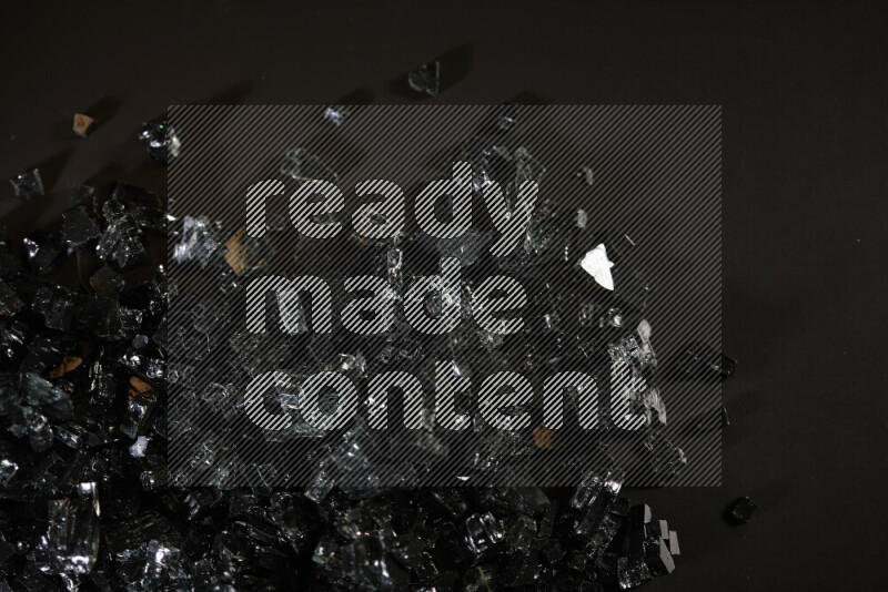 Transparent black fragments of glass scattered on a black background