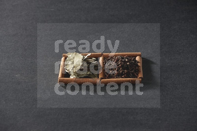 2 squares of cinnamon sticks full of cloves and bay laurel leaves on black flooring