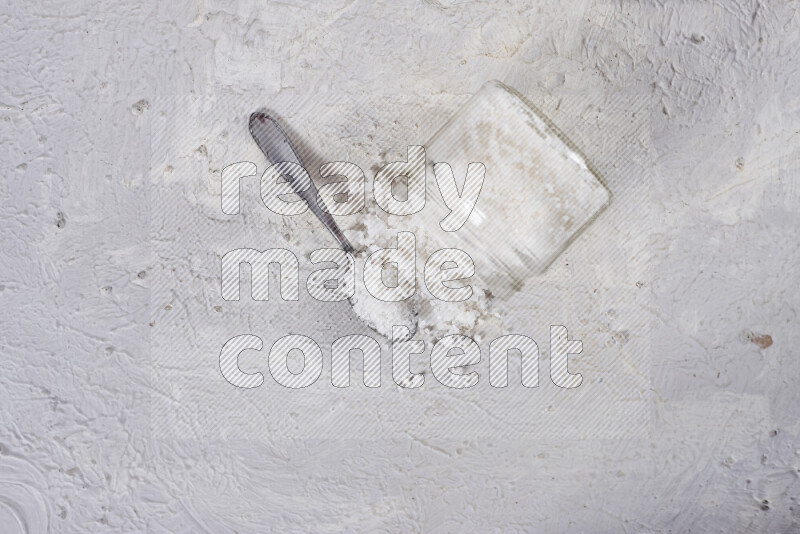 A glass jar full of coarse sea salt crystals on white background