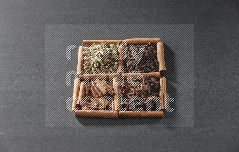 4 squares of cinnamon sticks full of cinnamon, cardamom, cloves and star anise on black flooring