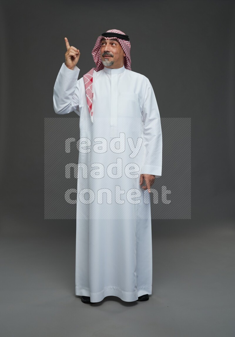 Saudi man with shomag Standing Interacting with the camera on gray background