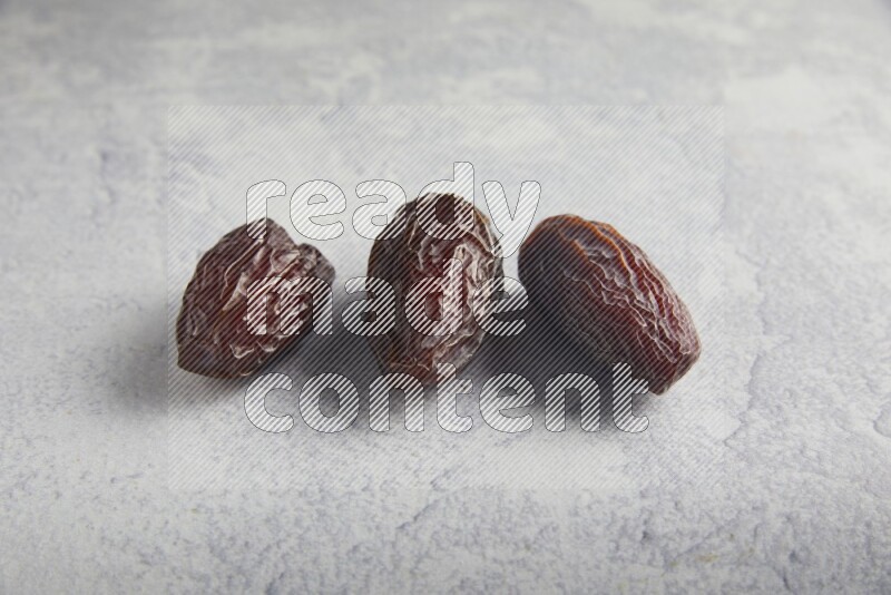 three madjoul dates on a light grey background