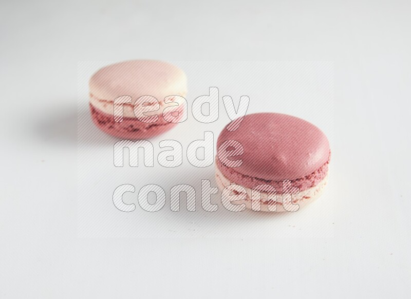 45º Shot of two Pink Litchi Raspberry macarons on white background