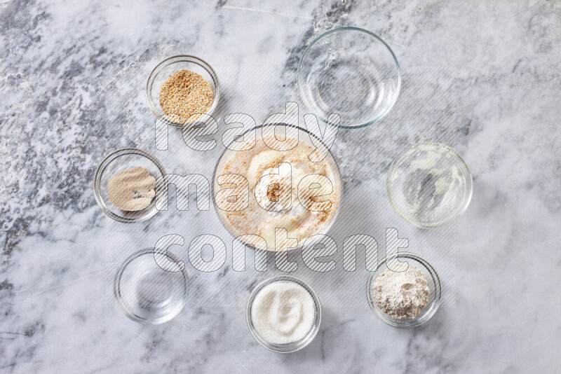 Kahk step by step with its ingredients ghee, sugar, flour, sesame, yeast, water and kahk flavor on grey marble background
