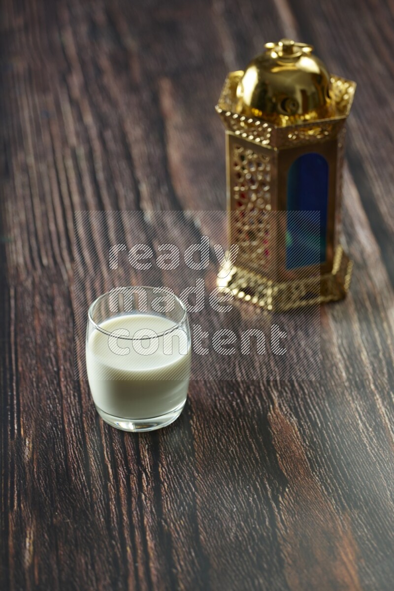 A golden lantern with different drinks, dates, nuts, prayer beads and quran on brown wooden background