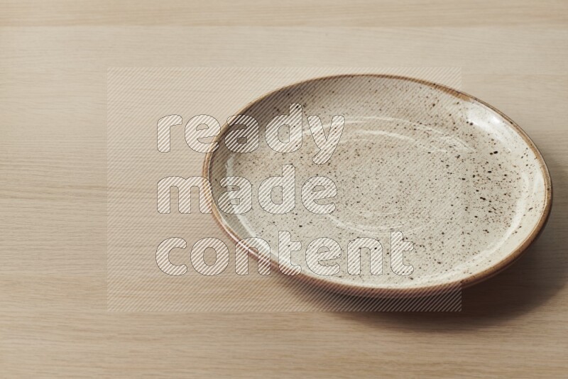 A beige pottery plate on light wooden background