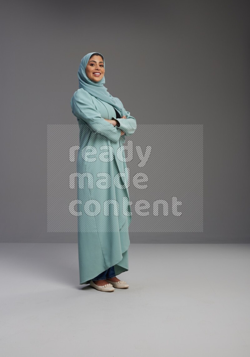 Saudi Woman wearing Abaya standing with crossed arms on Gray background