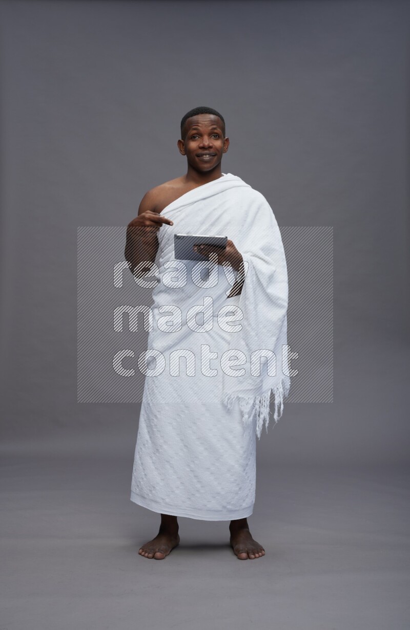 A man wearing Ehram Standing working on tablet on gray background