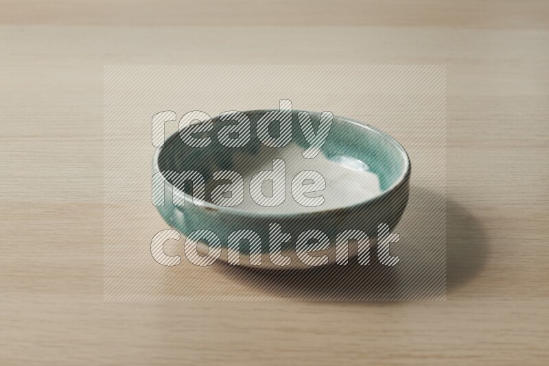 A multicolored pottery bowl on light wooden background