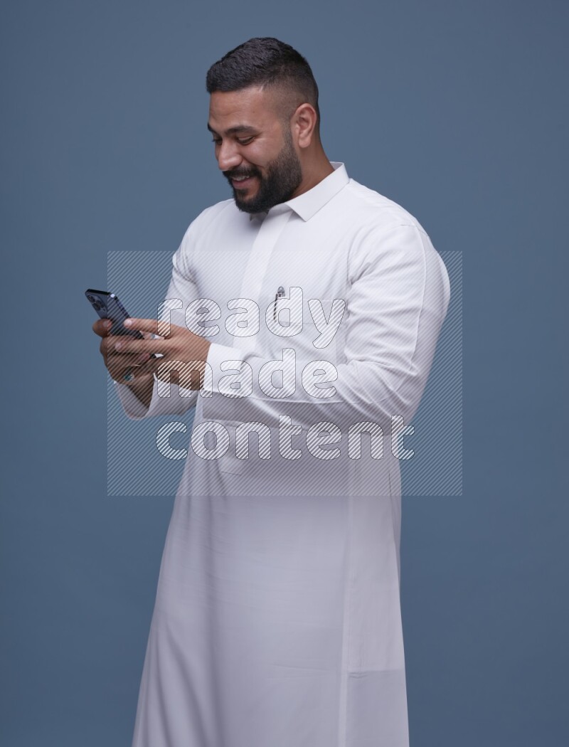 A man Texting on Blue Background wearing Saudi Thob