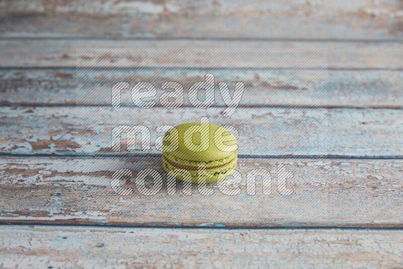45º Shot of Green Pistachio macaron on light blue wooden background