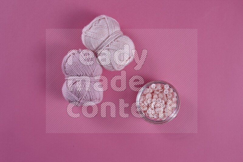 A pink collection of sewing and tailoring tools arranged on a pink background