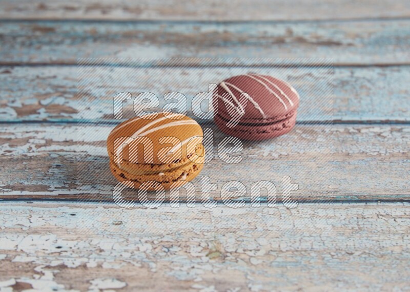 45º Shot of of two assorted Brown Irish Cream, and Red Poppy Flower macarons  on light blue background