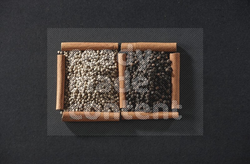 2 squares of cinnamon sticks full of white peppers and black peppers on black flooring