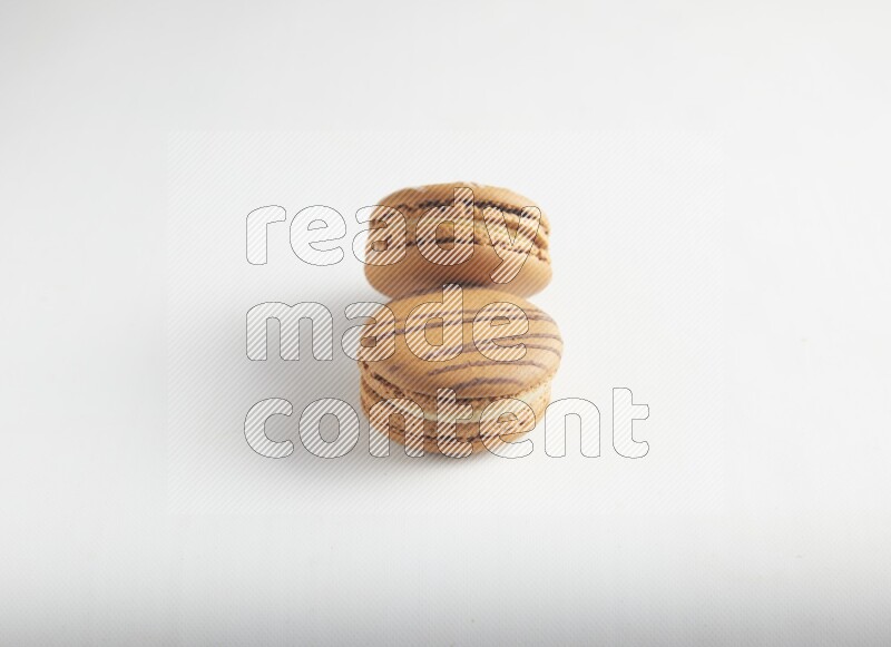 45º Shot of of two assorted Brown Irish Cream, and light brown  Almond Cream macarons on white background