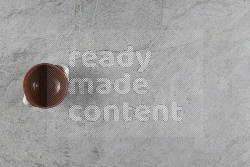 A multicolored pottery pot with its lid on grey marble background