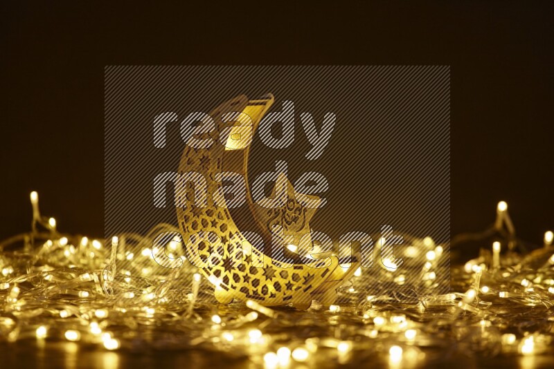 A traditional ramadan lantern surrounded by glowing fairy lights in a dark setup