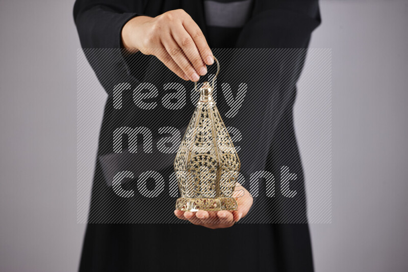A woman in black abaya holding different ramadan lanterns in different positions