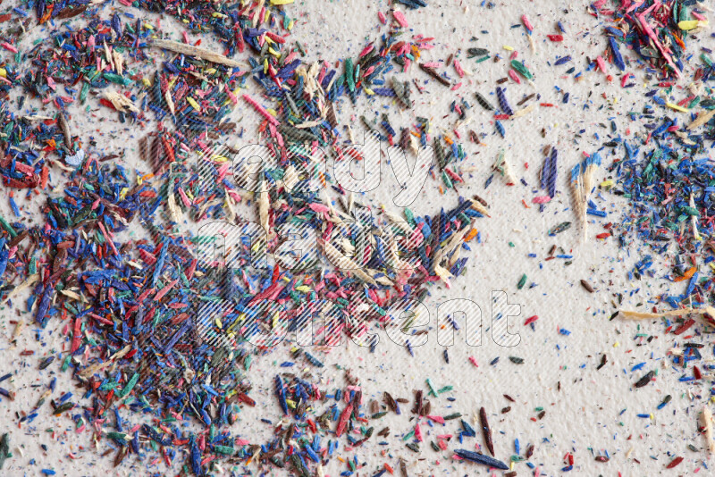 This image showcases a vibrant multicolored pencil shavings scattered on grey background