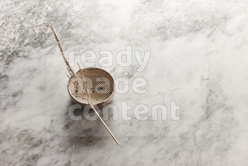 Wheat stalks on multicolored pottery bowl on grey marble background