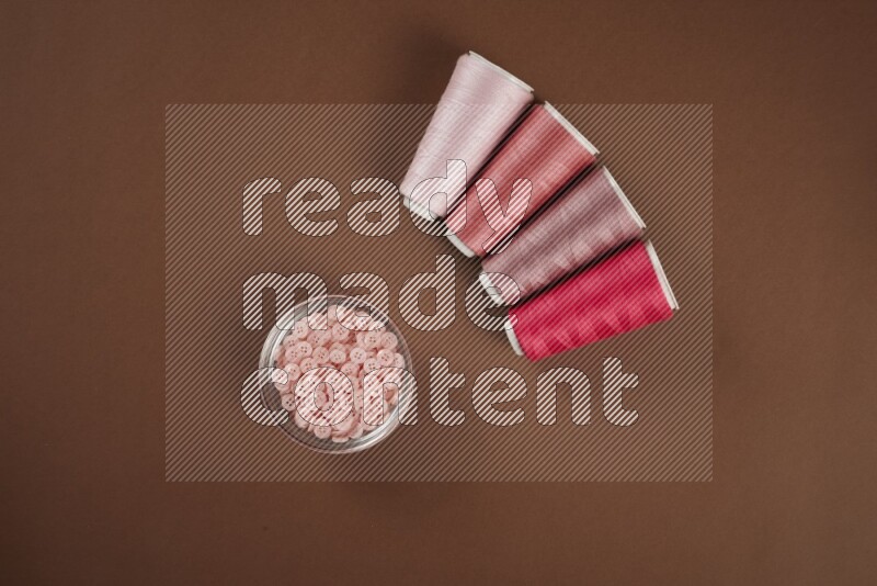 A pink collection of sewing and tailoring tools arranged on a brown background