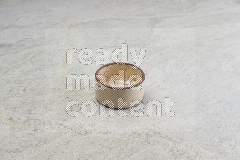 A small beige pottery bowl on grey marble background
