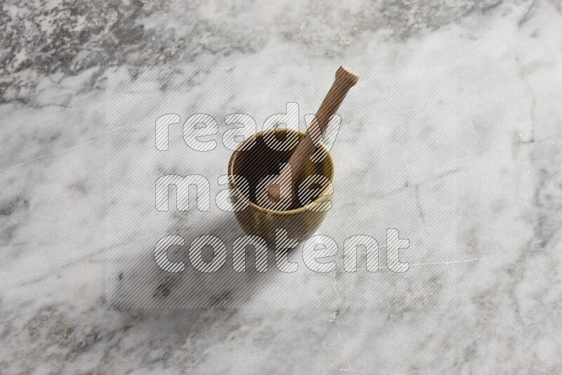 Multicolored pottery cup with wooden honey dipper in it on grey marble background