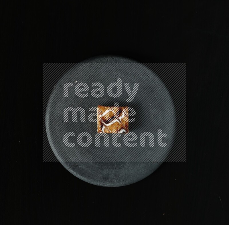 Assorted desserts in a black pottery plate on black background