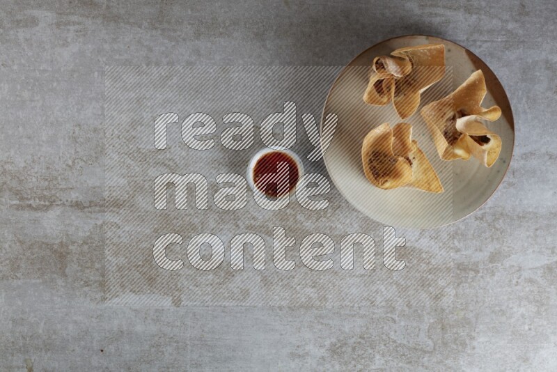 wonton cups with soy sauce ramkin on multi colored pottery on grey textured counter top